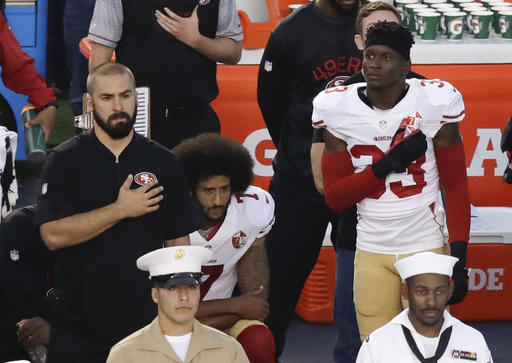 In this Thursday, Sept. 1, 2016 file photo, San Francisco 49ers quarterback Colin Kaepernick, middle, kneels during the national anthem before the team's NFL preseason football game against the San Diego Chargers, in San Diego. NFL Commissioner Roger Goodell disagrees with Kaepernick's choice to kneel during the national anthem, but recognizes the quarterback's right to protest.  (AP Photo/Chris Carlson, File)