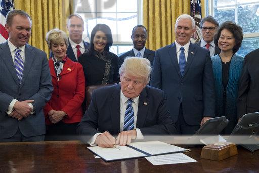President Trump signs one of the 17 executive orders.