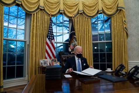 President Joe Biden signs a series of executive orders in the Oval Office of the White House, Wednesday, Jan. 20, 2021, in Washington. (AP Photo/Evan Vucci)