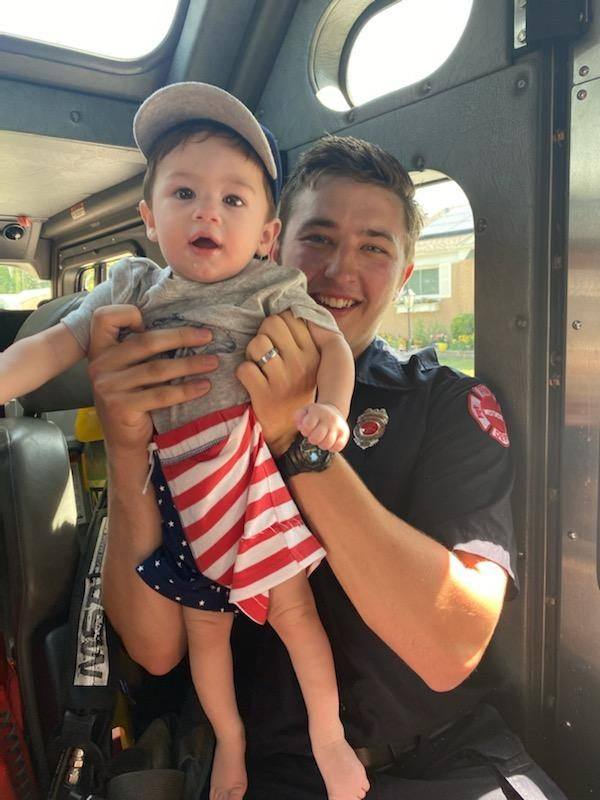 Alumnus Sean Johnson (Class of 2015), holds his son in a Fourth of July Parade. 